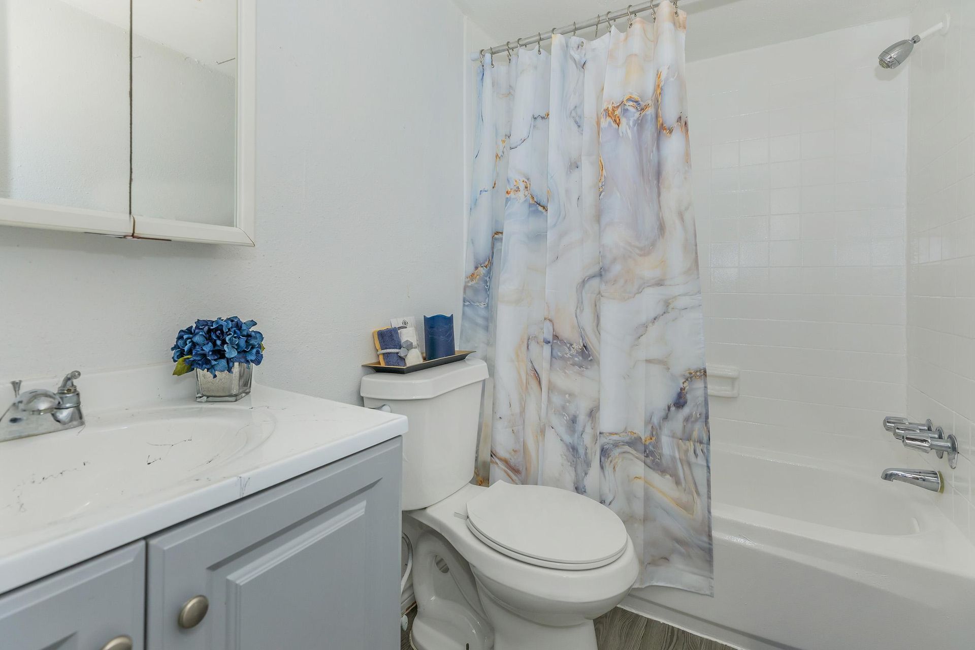 Bathroom with vanity, toilet, and marble-pattern shower curtain.