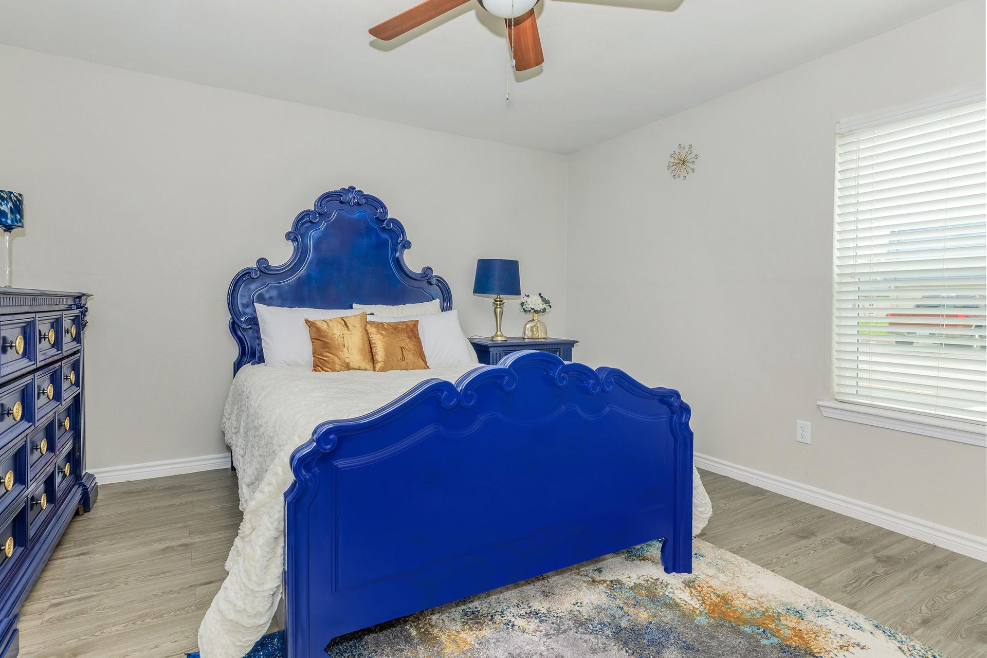 Blue ornate bed with matching dresser in a bright bedroom.