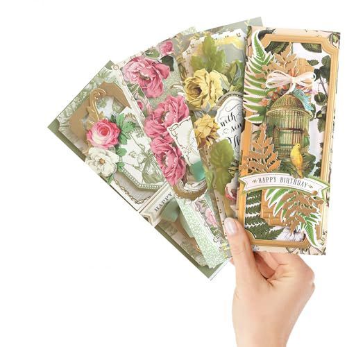 A hand holds a fan of four ornate, vintage-style greeting cards featuring floral patterns, botanical art, and gold accents.