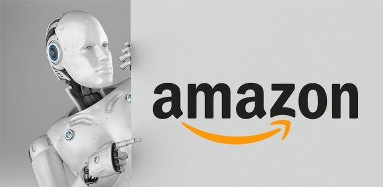 A white humanoid robot stands beside a large white board displaying the black and orange Amazon logo.