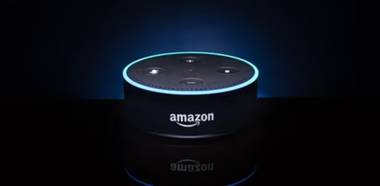 An Amazon Echo Dot smart speaker glowing with a blue circular light ring against a dark background.