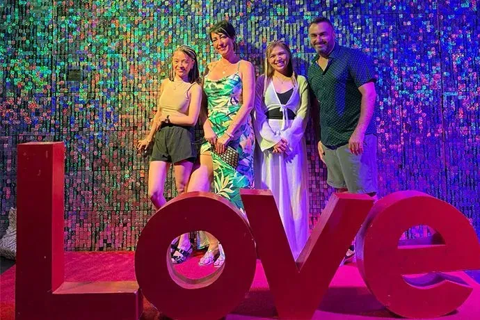 Four people stand behind a large, red 