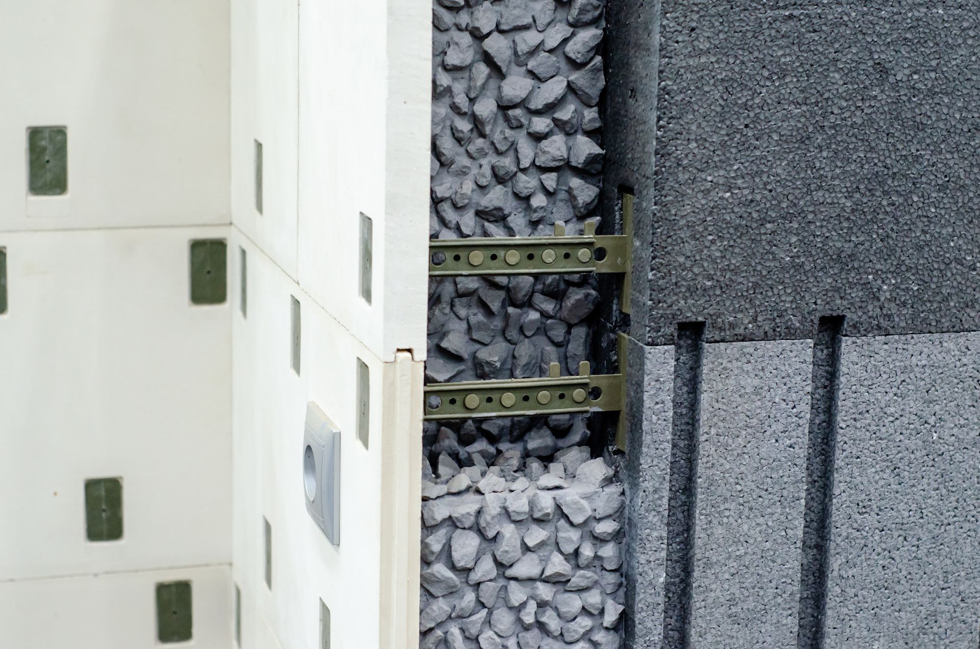 Cross-section of a building wall, showing layers of insulation, gravel, and structural components.