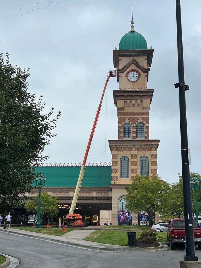 Workers on scaffolding painting a large red building exterior
