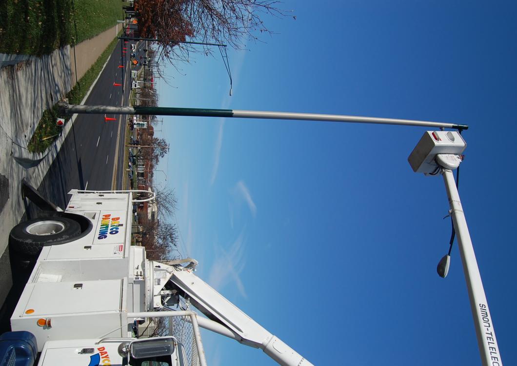 Dayco painting working to apply fresh paint to light posts in city