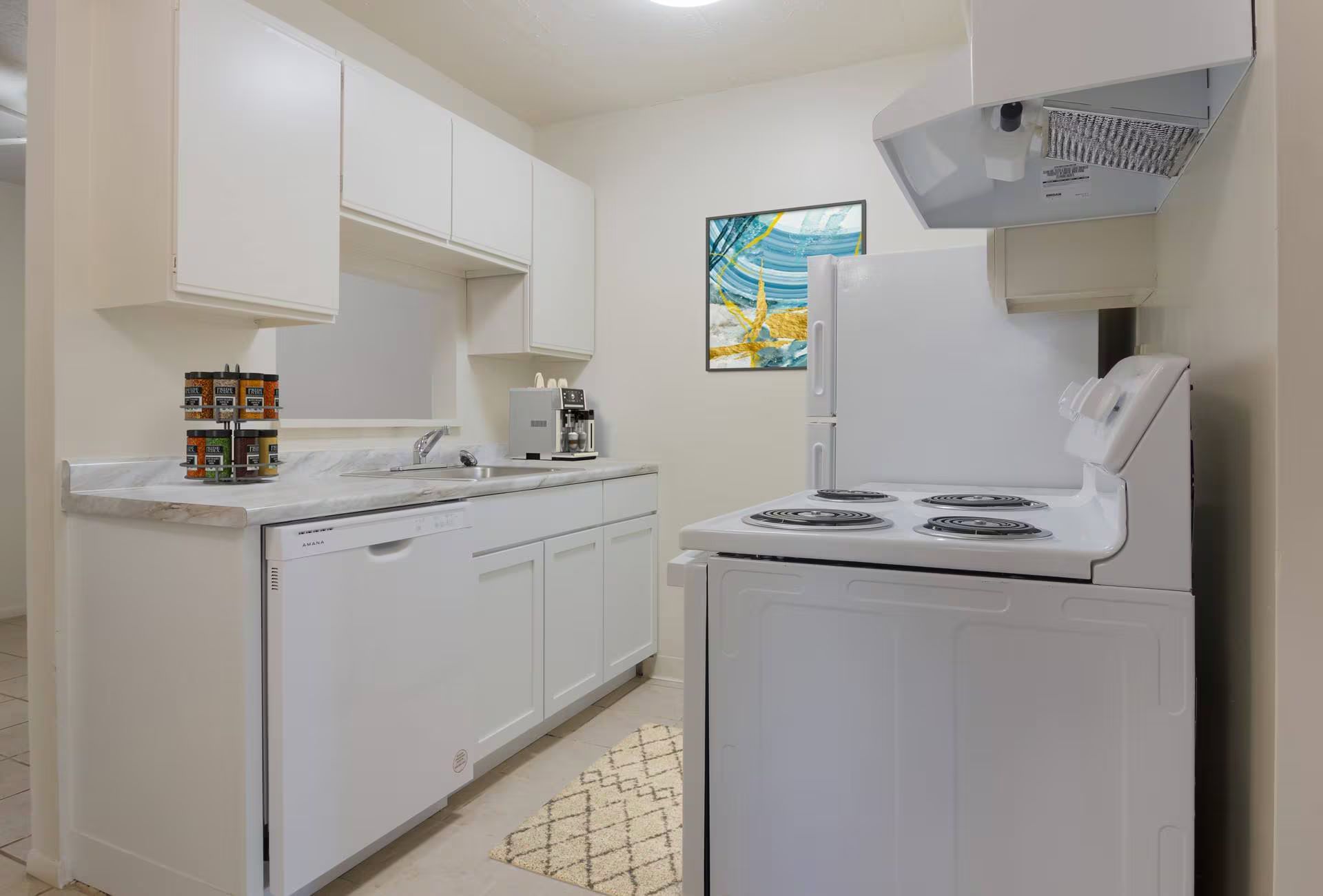 White kitchen with appliances, cabinets, and a colorful wall art.