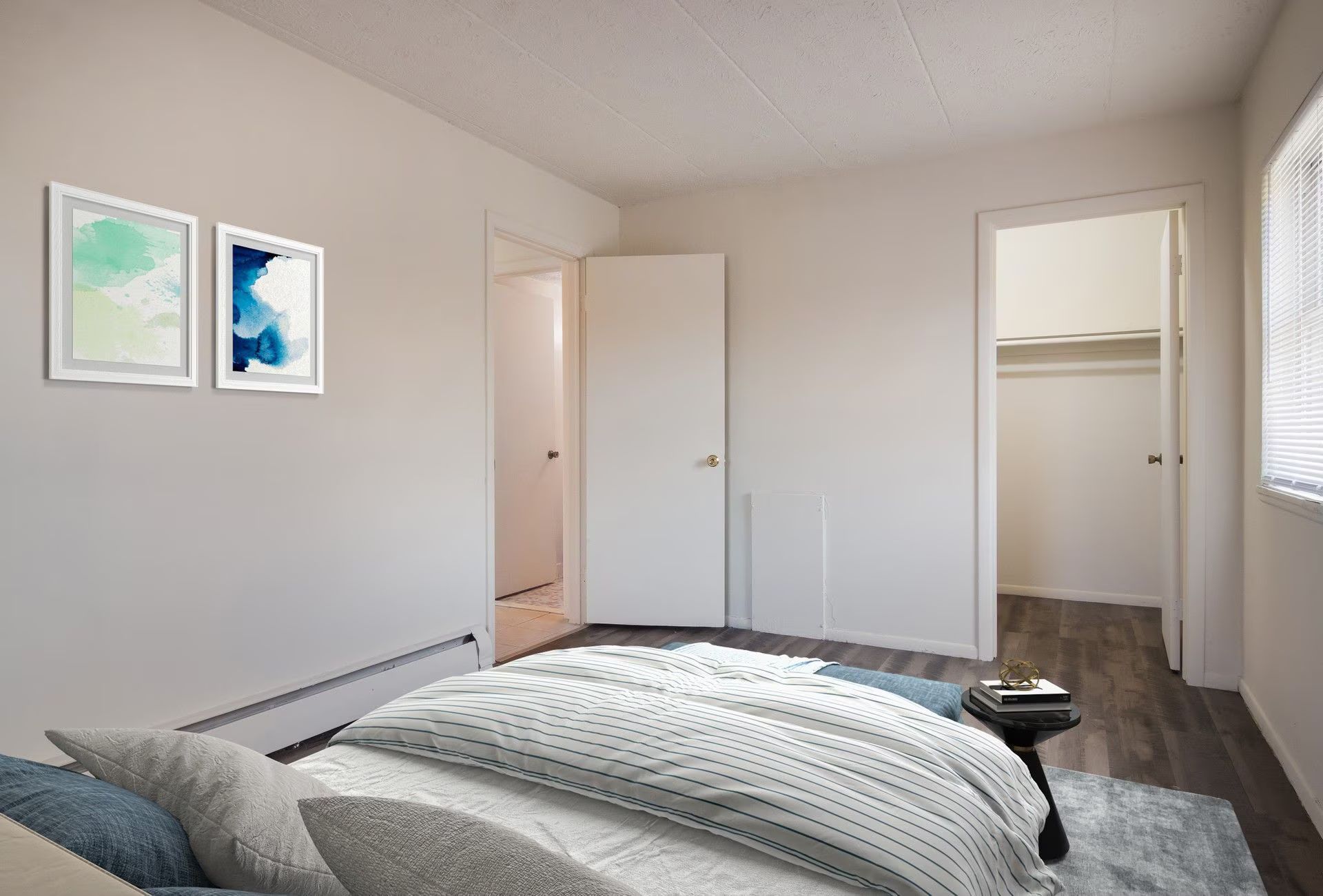 Bedroom with bed, closet, and two framed watercolor prints.