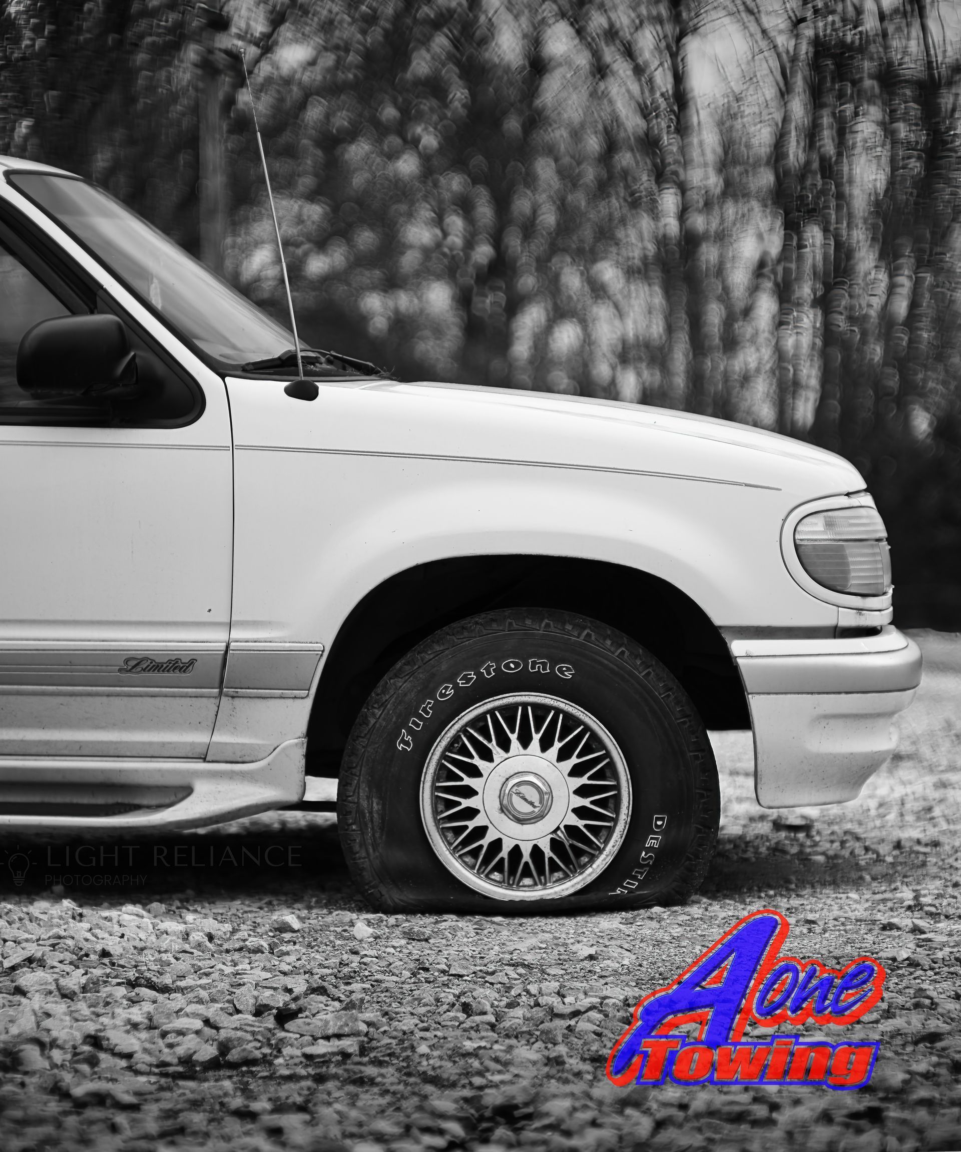 White SUV with a flat tire, on a gravel road.
