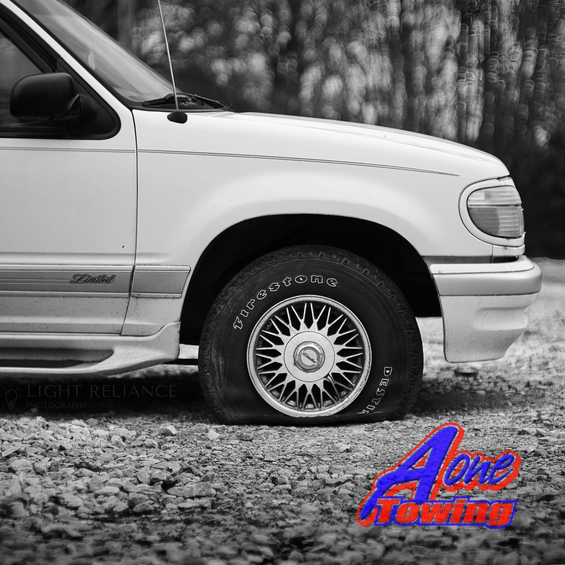 White SUV with a flat tire on gravel, 