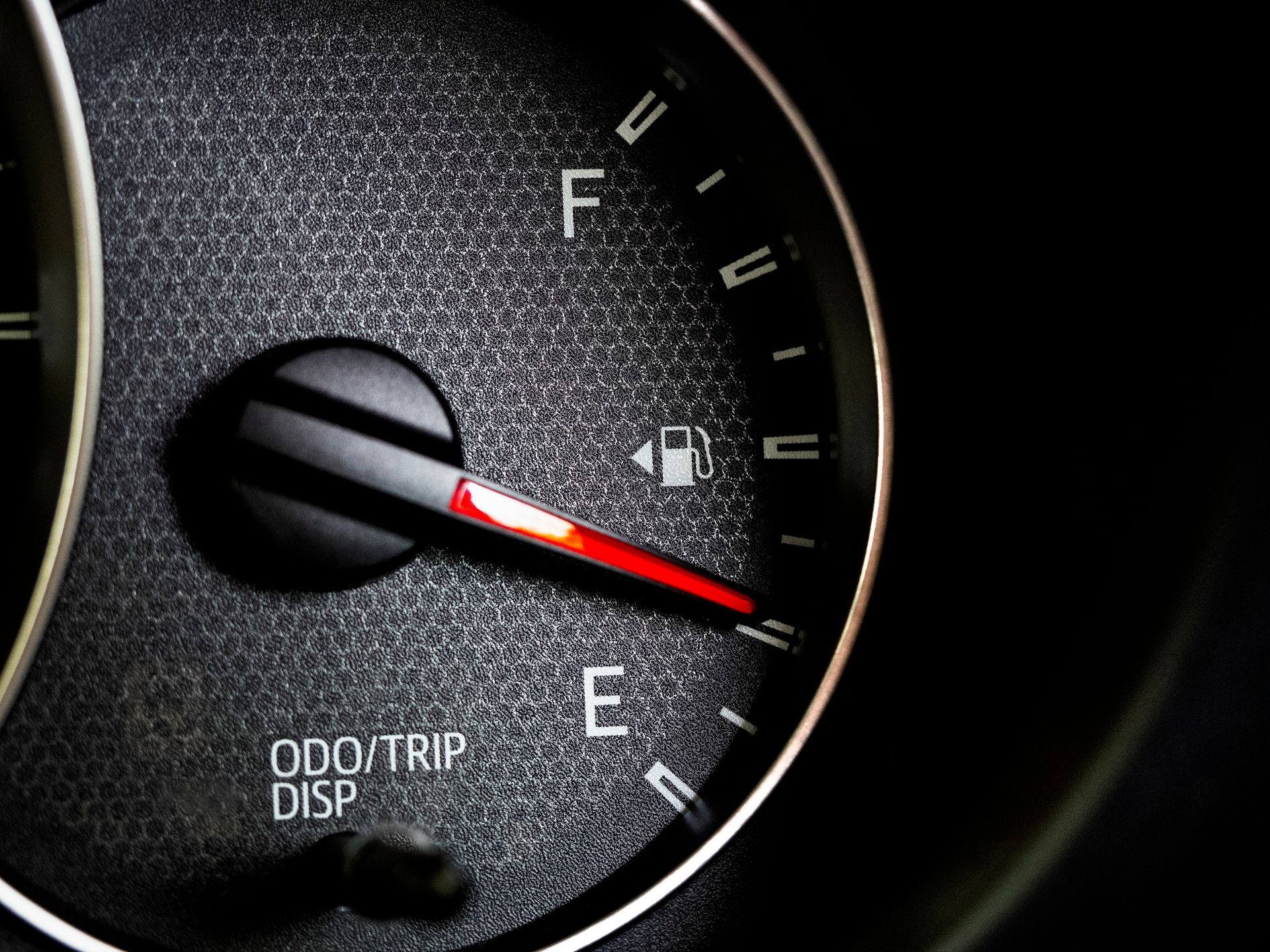Fuel gauge near empty, black dial, red indicator pointing toward 