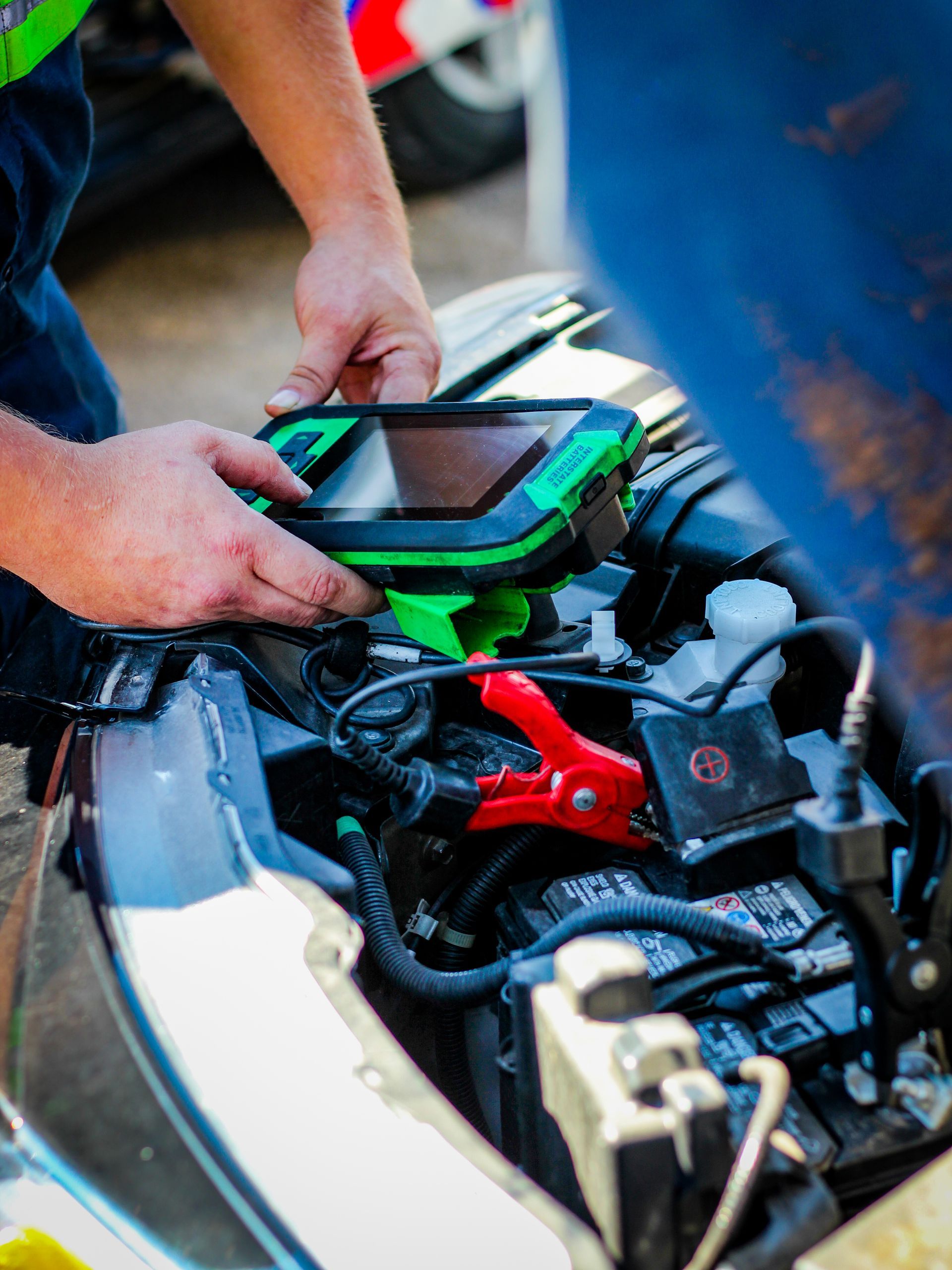 Red warning triangle on road in front of a broken-down car with hood open.
