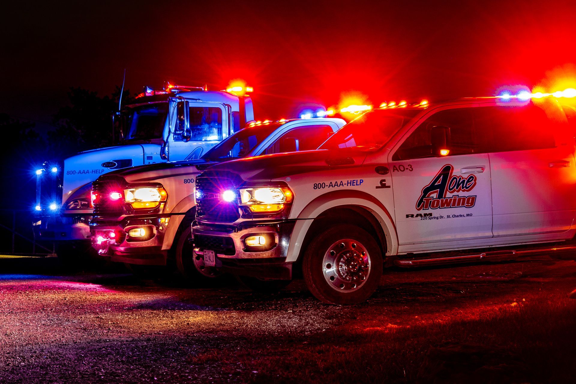 Tow trucks with flashing red and blue lights at night.