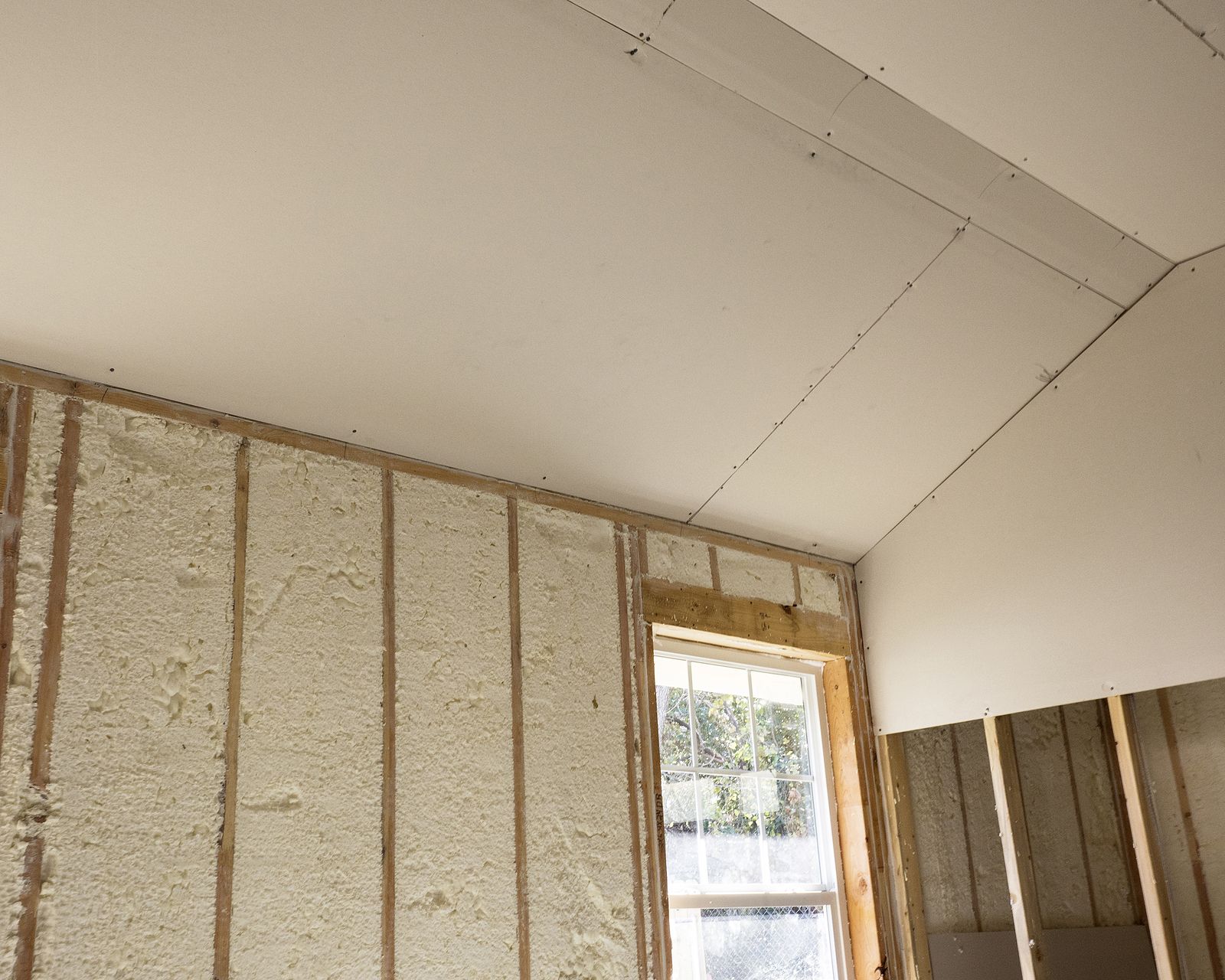 A room with foam insulation on the walls and ceiling and a window.