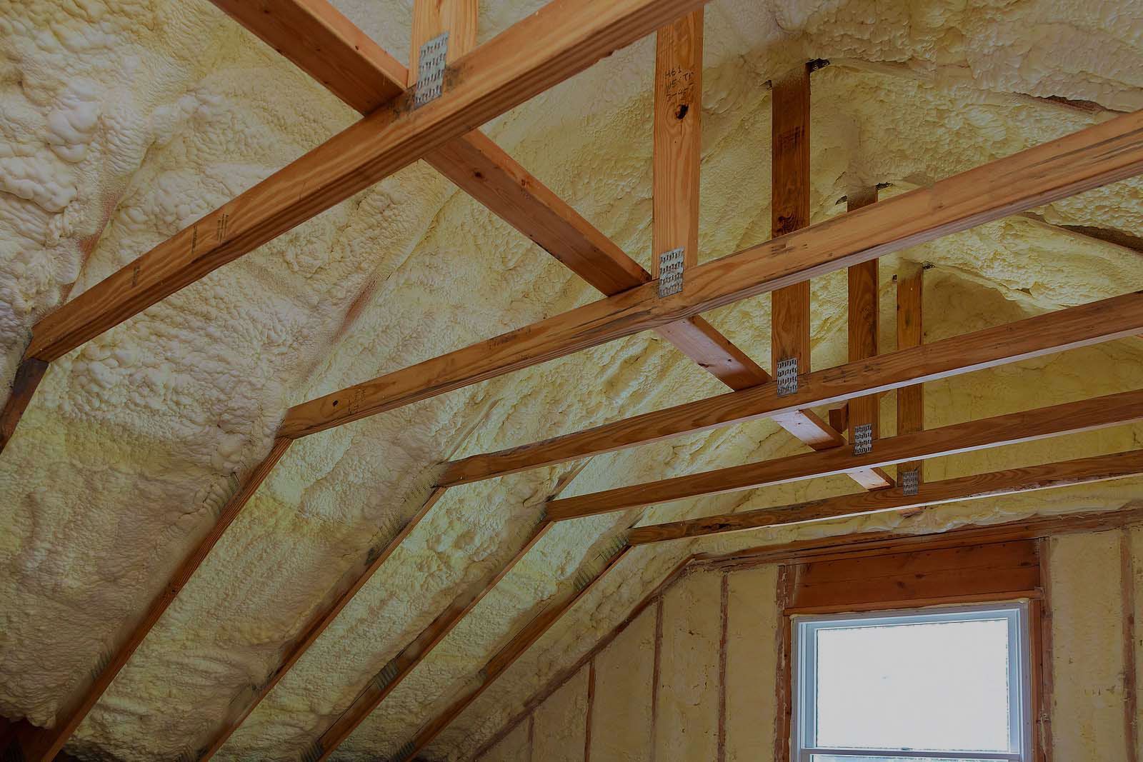 The ceiling of a house with wooden beams and foam on it.