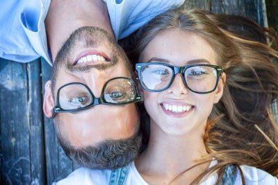 Family Eyewear — Couple Lying on Wooden Bench Wearing Eyeglasses in San Rafael, CA
