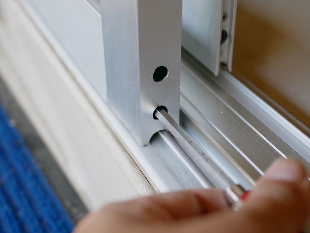 Person is Working on a Sliding Glass Door With a Screwdriver — Ezi Slide - Glass, Sliding, Track & Security Doors Repair in Tweed Heads, NSW