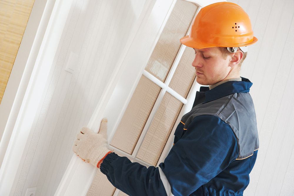 A Man Wearing A Hard Hat Is Holding A Door — Ezi Slide - Glass, Sliding, Track & Security Doors Repair in Tweed Heads, NSW