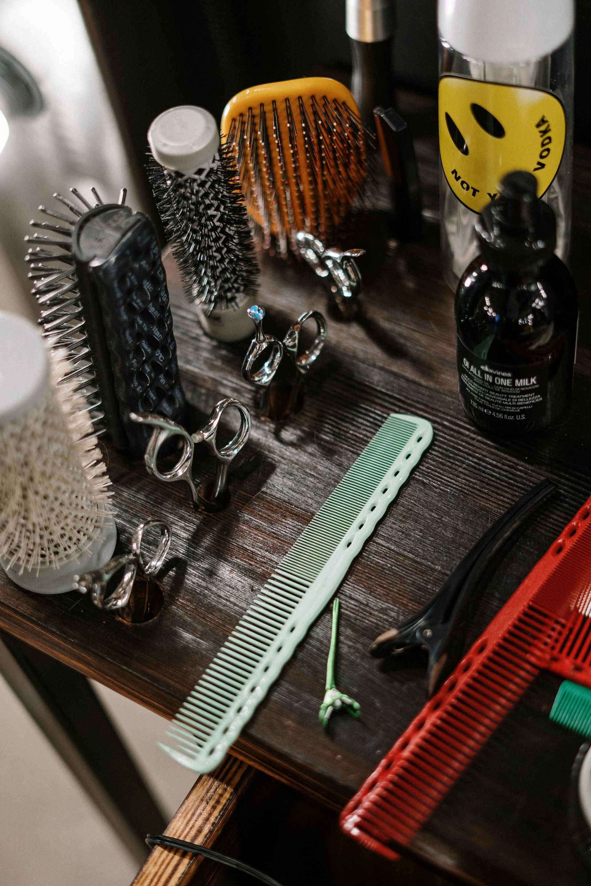 Close-up of hair styling tools including combs, brushes, and accessories on a wooden surface.