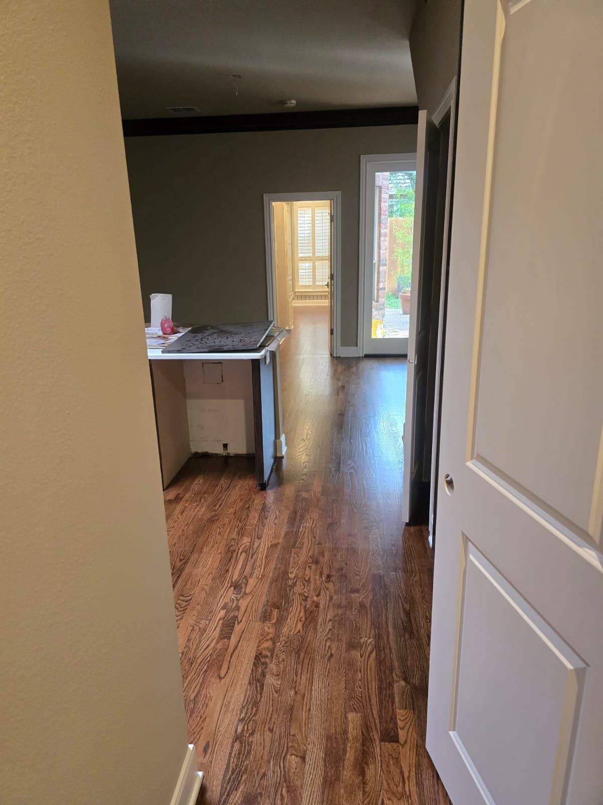 Looking down a hallway with wood flooring, the kitchen on the left and a door to a patio on the right.