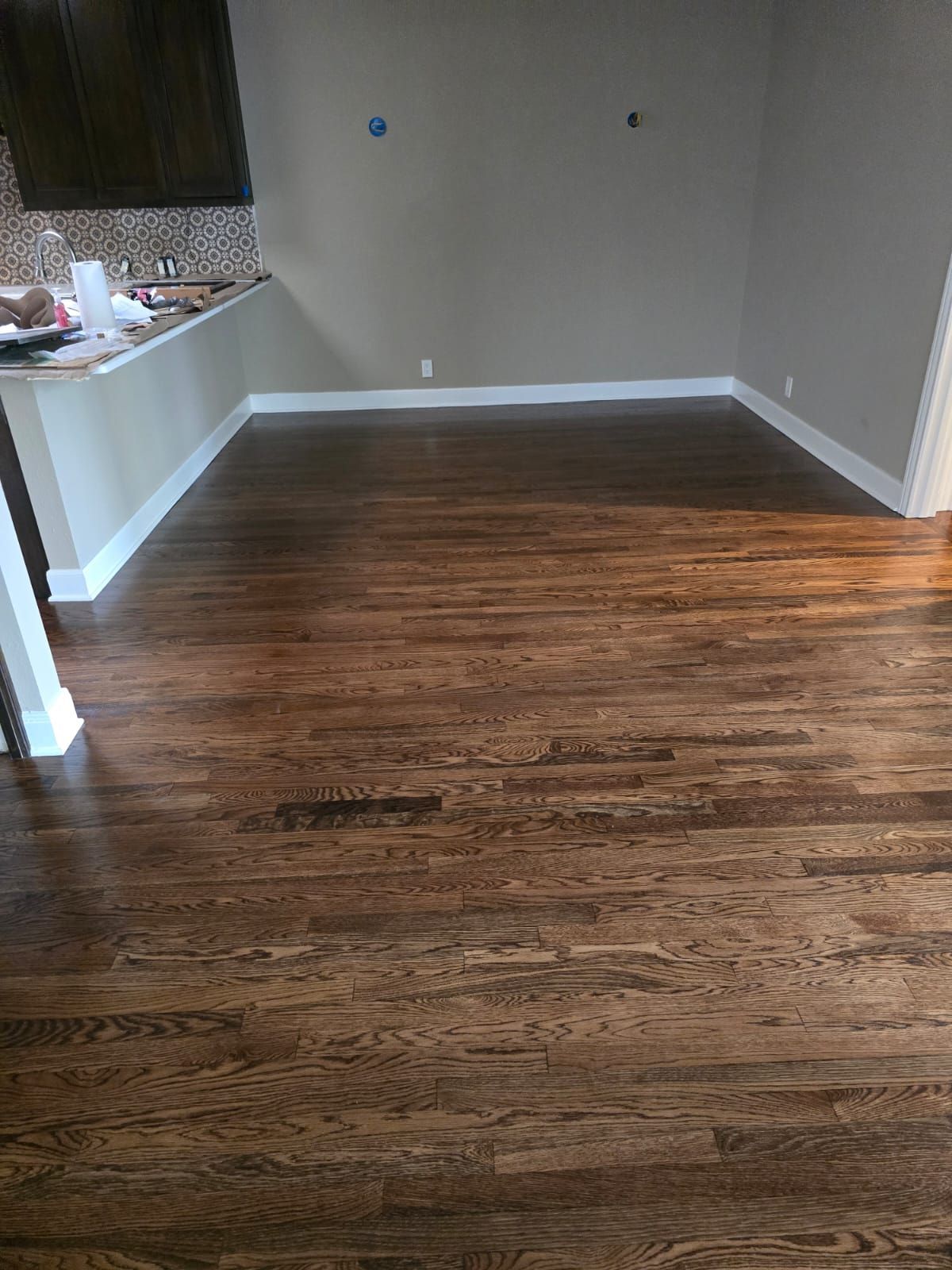 Dark hardwood floors in a room with white trim and beige walls.