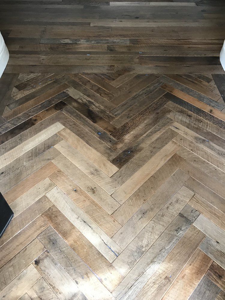 A close up of a wooden floor with a herringbone pattern.
