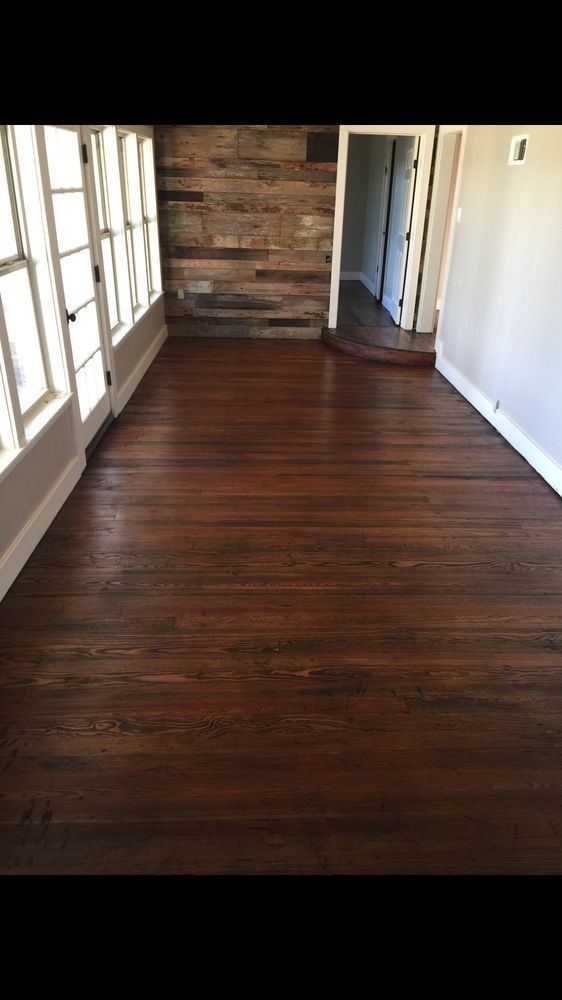 A living room with a wooden floor and a stone wall.