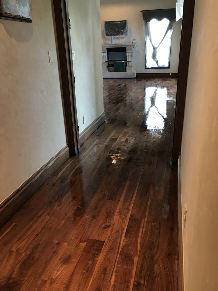 A hallway with hardwood floors and a fireplace in the background.