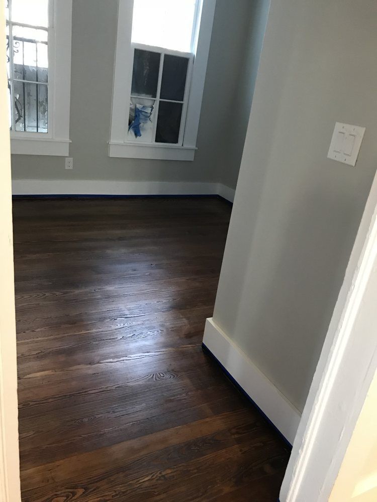 An empty room with hardwood floors and two windows.