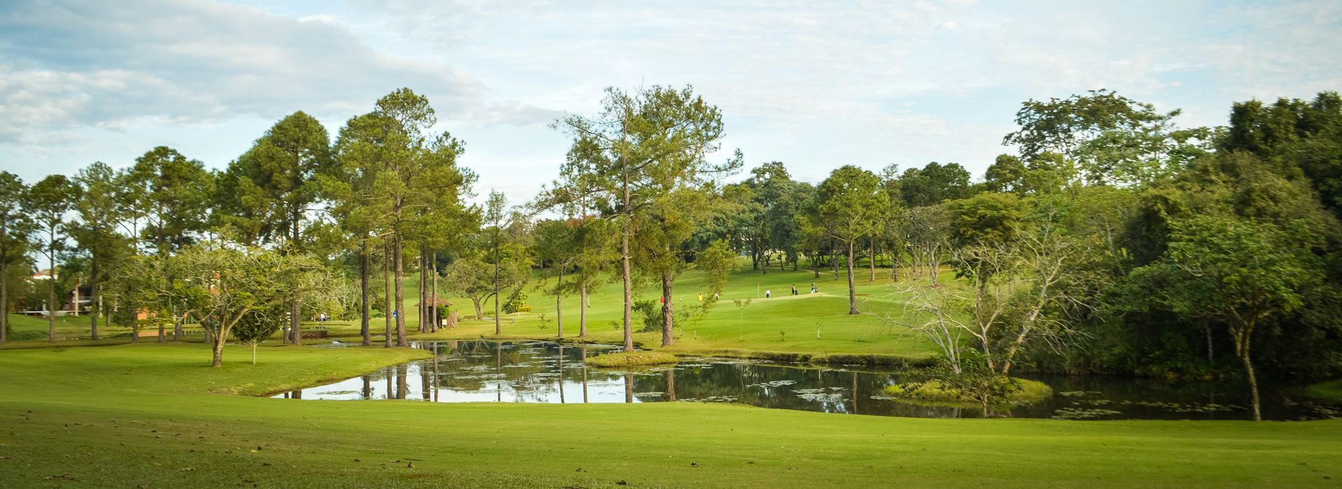 Hay un estanque en medio de un campo de golf rodeado de árboles. Bisinii Hotel Boutique