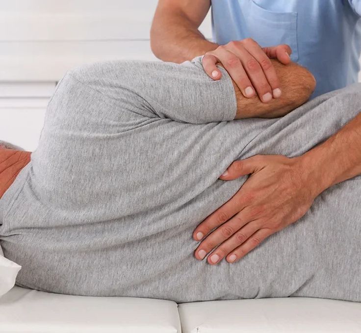 A man is laying on a bed getting a massage from a doctor.