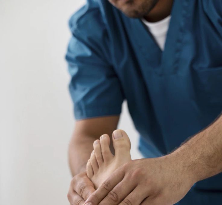 A man in a blue scrub is examining a patient 's foot