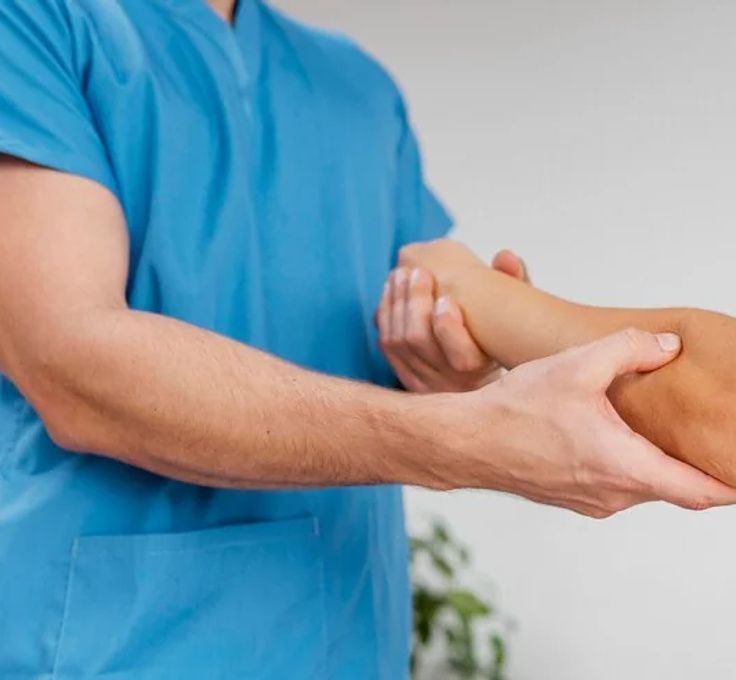 A man in a blue scrub is holding the arm of a woman.