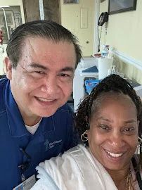 A man and a woman are posing for a picture in a hospital room.