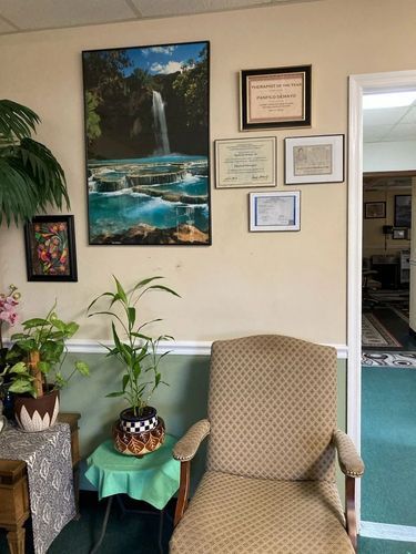 A chair in a room with a picture of a waterfall on the wall.