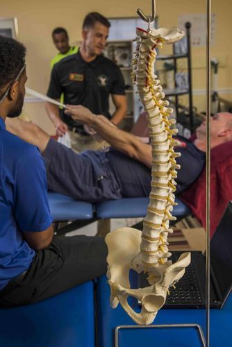 A man is laying on a table with a model of a spine.