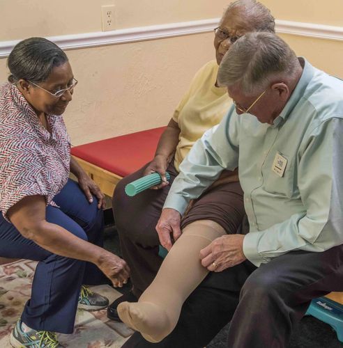 A woman is helping a man put on a pair of stockings