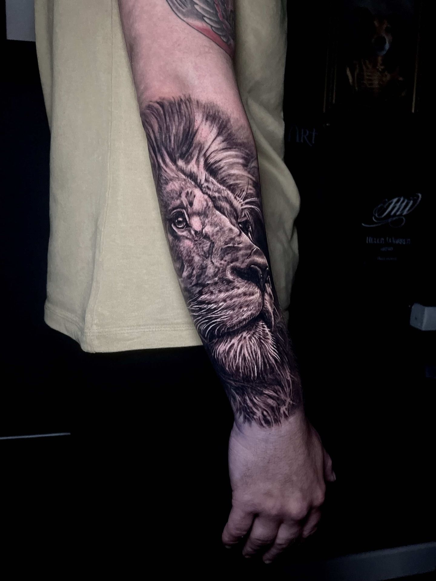 Realistic black and white lion tattoo on a person's forearm.