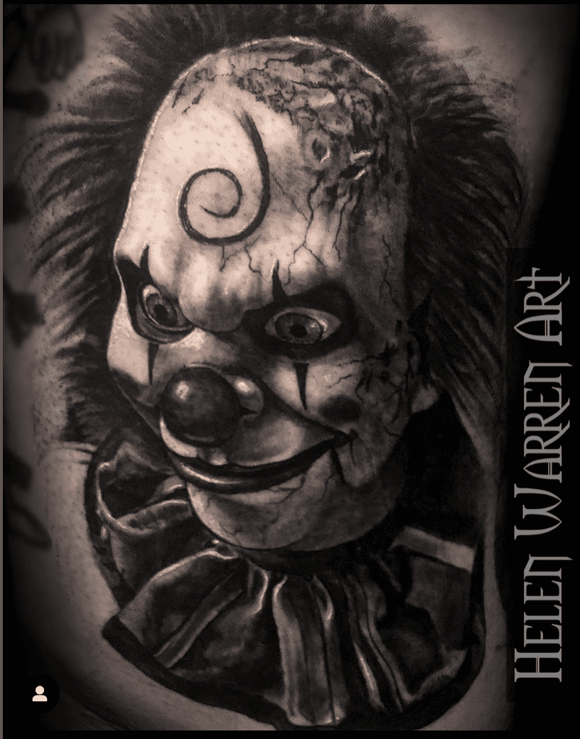 Black and white tattoo of a creepy clown head with cracks, swirly symbol, and ruff.