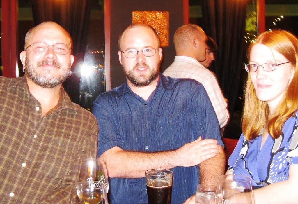 Three people inside a dimly lit restaurant. 
