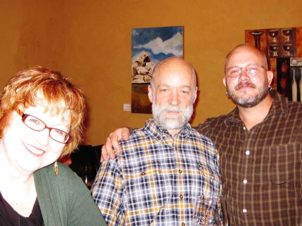 Three people smiling and posing for a photo indoors.