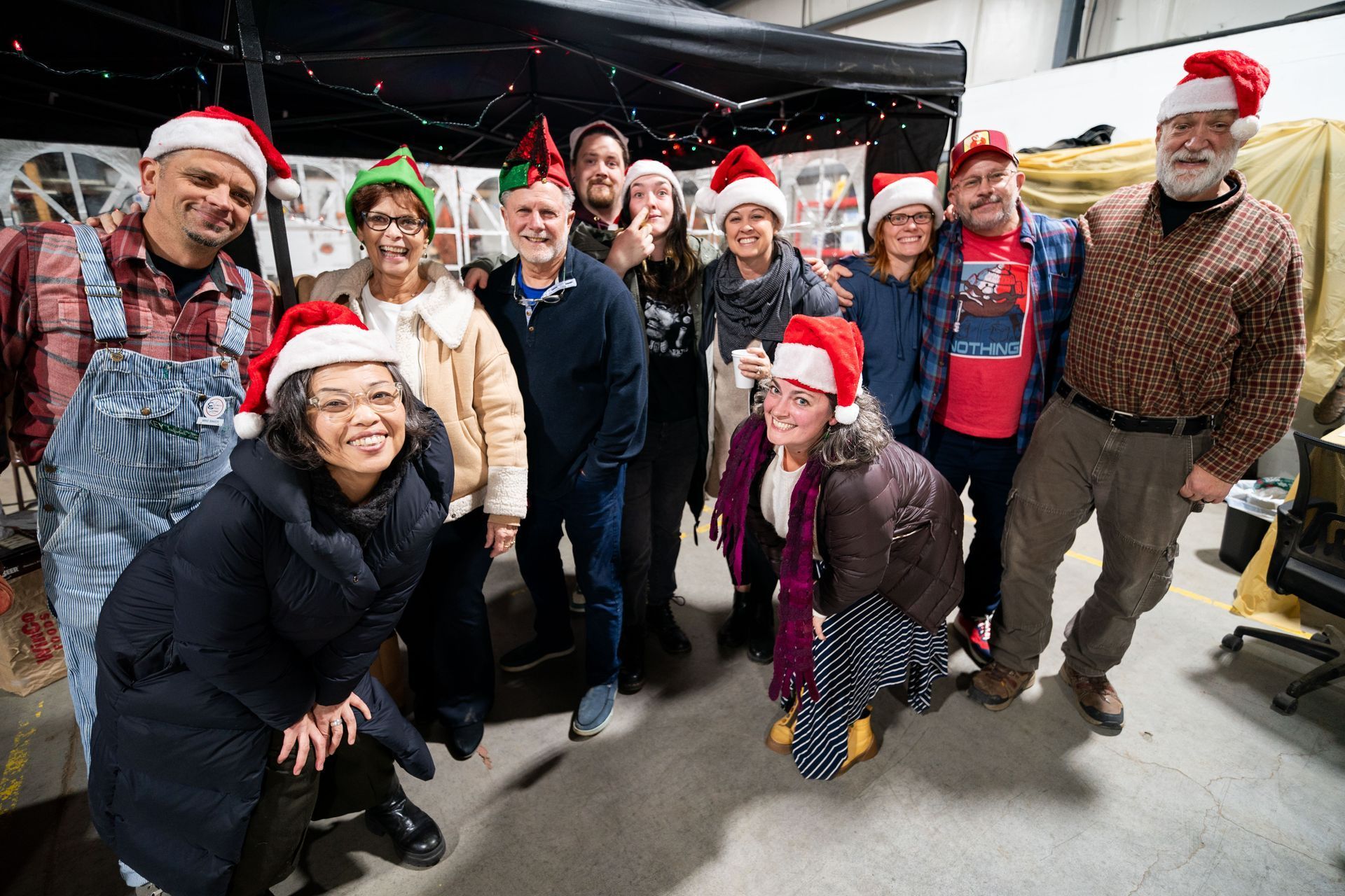 Group of people wearing Santa hats posing for a photo in a warehouse.