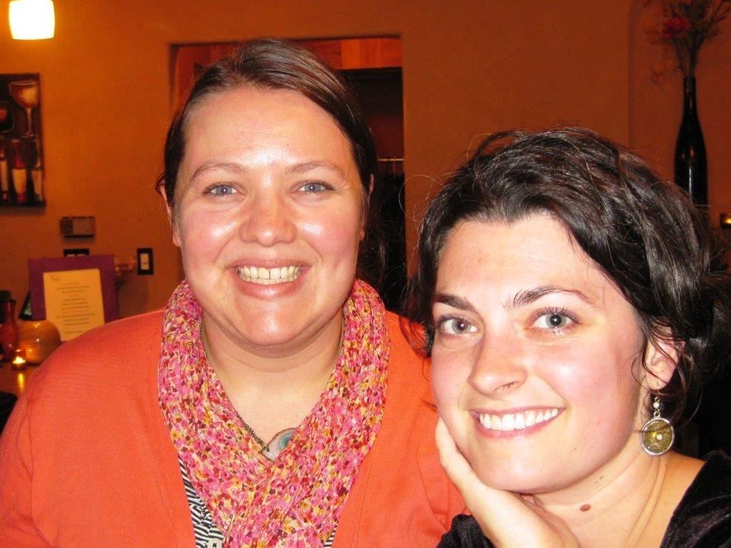 Two smiling women indoors.