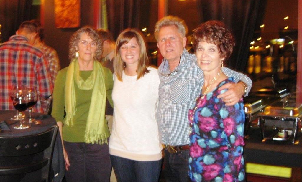 Four people at an event: two women, a man with his arm around one woman.
