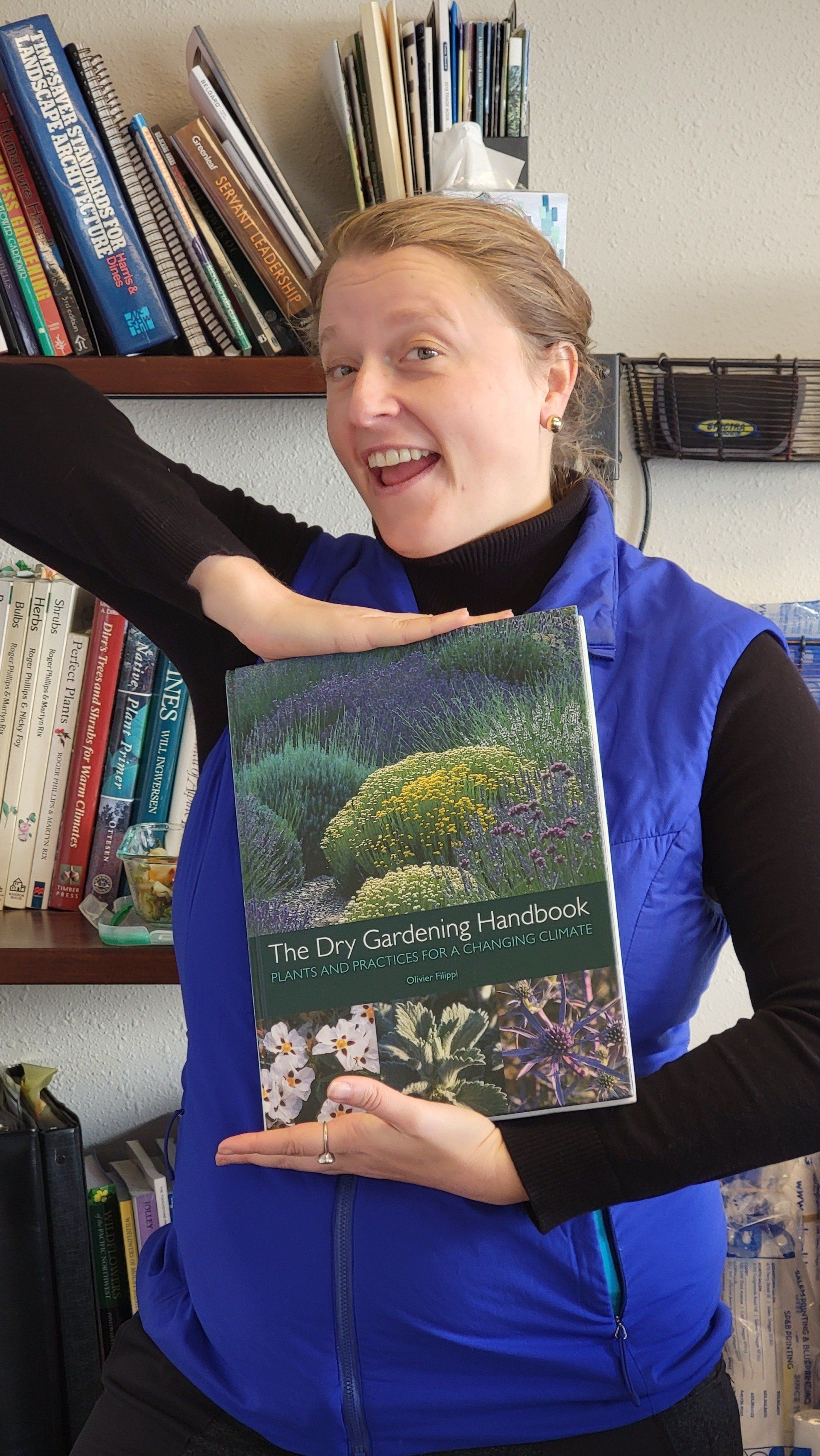 Woman in blue vest holds book titled, 