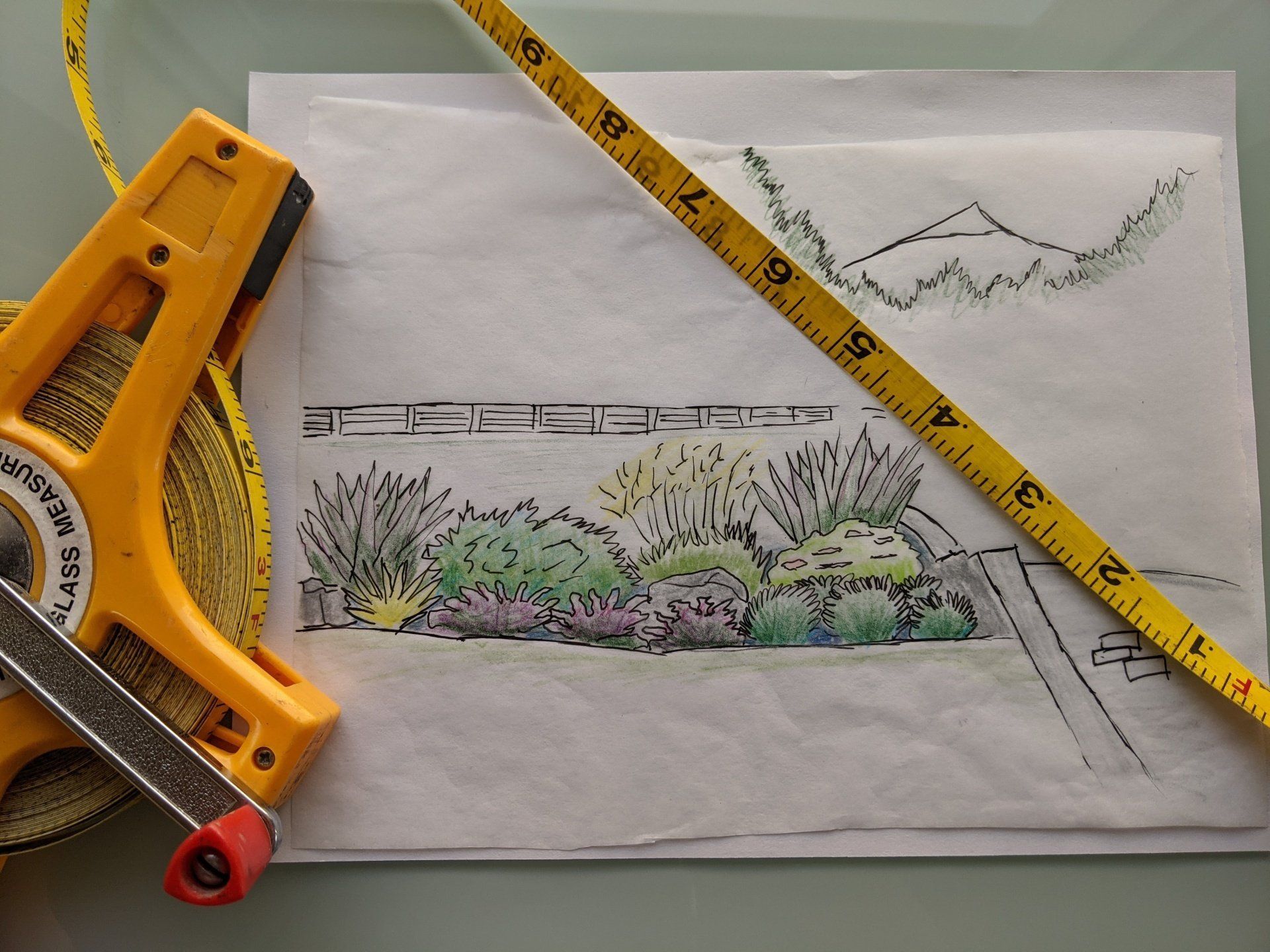 A hand-drawn garden landscape sketch with a yellow tape measure resting on it.