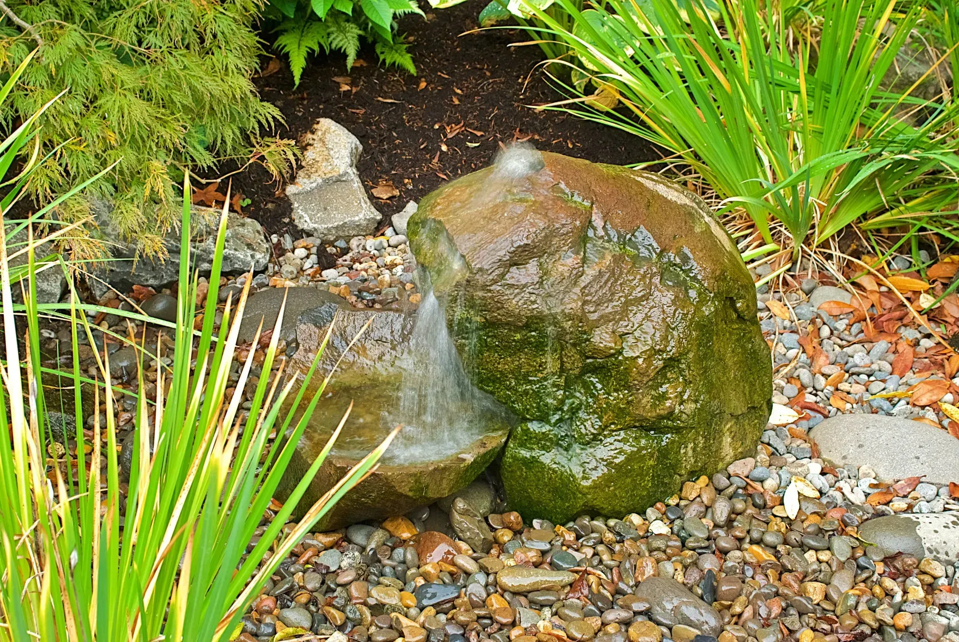 A small rock water fountain in a garden setting. 