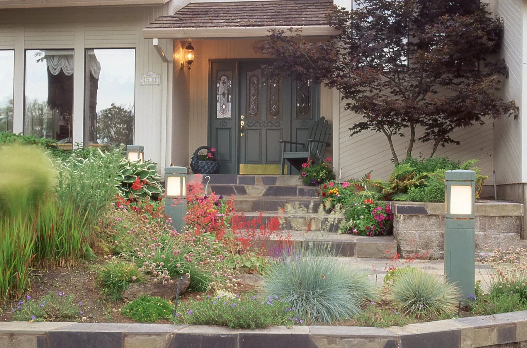 A house entrance with a stone walkway and landscaping. 