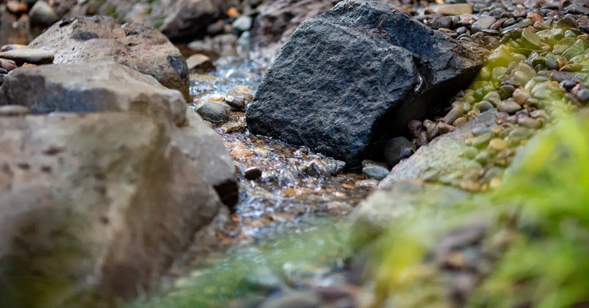 A small stream flows over rocks; green moss grows on the edges.