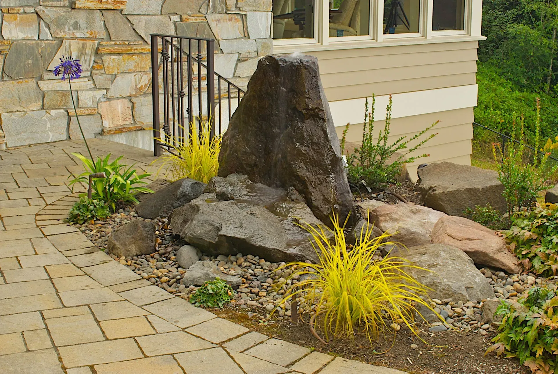 A water feature with a large, dark rock, surrounded by smaller rocks.