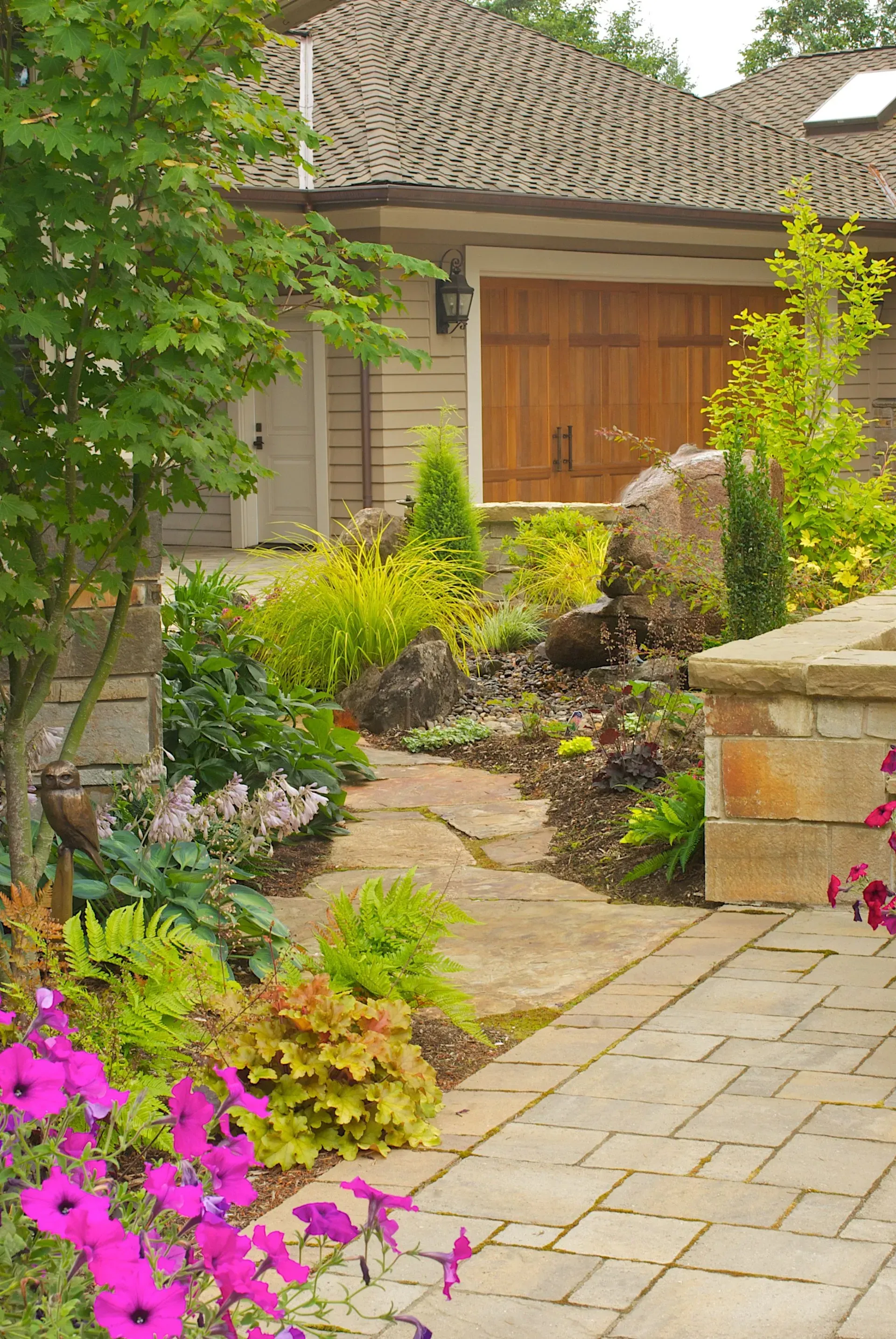 Stone pathway leads to a garden with colorful flowers and lush greenery.